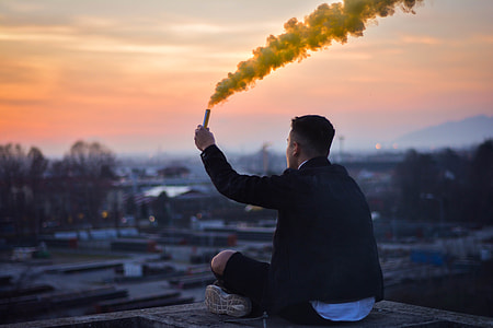 man sitting on top of a building holding yellow flare stick thumbnail