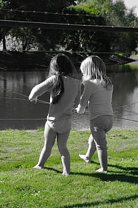 grayscale photography of two girls standing beside body of water thumbnail