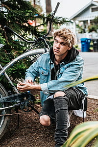 man wearing denim jacket beside bike thumbnail