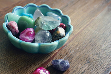 assorted-color rock collection on and beside teal ceramic bowl thumbnail