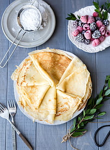 pancakes on white ceramic plate beside raspberries on saucer with two stainless steel forks thumbnail