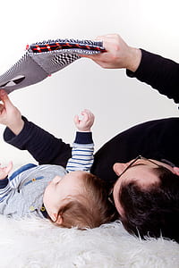 man lying on white fleece cushion beside baby thumbnail