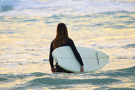 person holding surfboard in body of water thumbnail