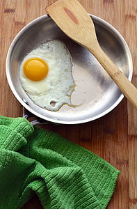 fried egg in round gray frying pan under brown wooden ladle thumbnail