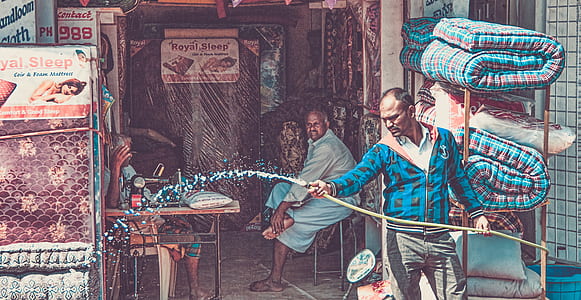 man holding water hose near sitting man inside store thumbnail