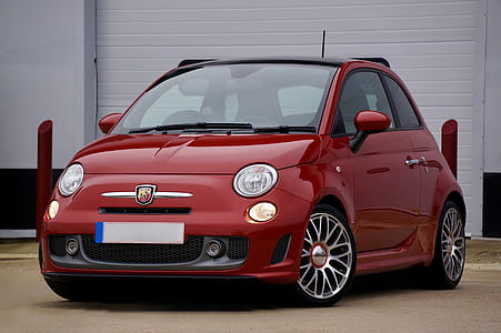 red FIAT 500 3-door hatchback parked beside white concrete building thumbnail