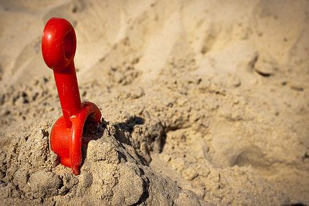 red plastic scoop on brown sand thumbnail