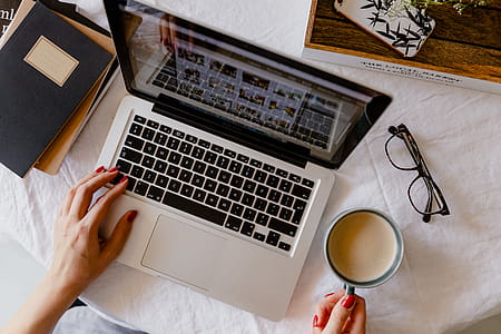 A woman works at a desk with a laptop and a cup of coffee thumbnail