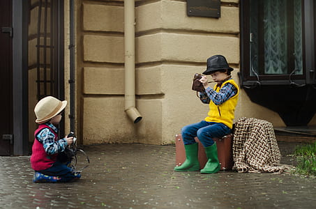 boy sitting on case taking photo of child on floor thumbnail