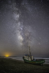 green and white boat near seashore thumbnail