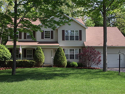 white wooden 2-storey house with garage beside trees thumbnail