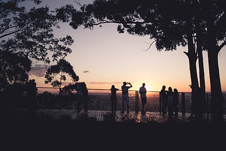 silhouette photo of people standing in front of railing during golden hour thumbnail