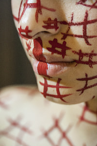 close-up and selective focus photography of person's face with red number sign markings thumbnail
