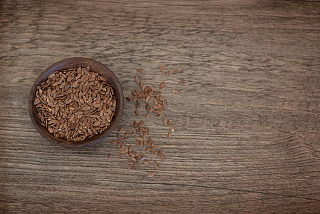 bowl of brown seeds on wooden surface thumbnail