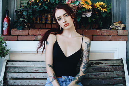 woman wearing black spaghetti strap top sitting on grey wooden bench thumbnail