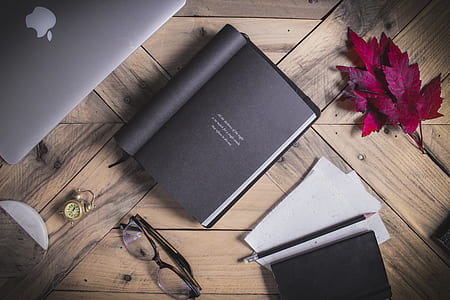 book beside pen and eyeglasses on table thumbnail