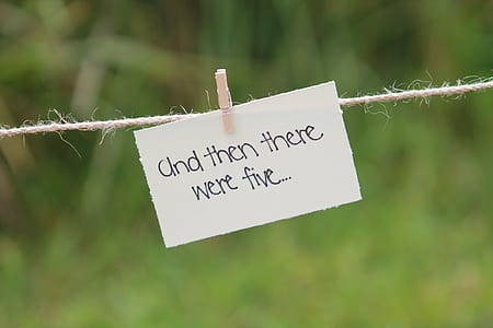 white paper with text hangs clipped from beige rope on selective focus photo thumbnail