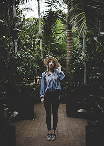 woman standing near trees holding her hat thumbnail