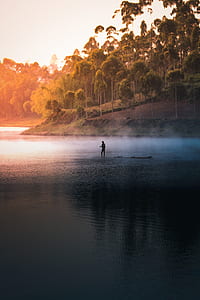 man standing on raft near green trees during daytime thumbnail