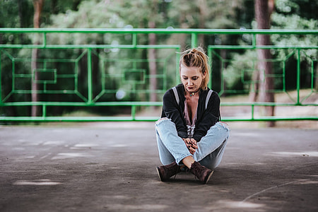 Blonde woman in a black jacket and ripped jeans by a green handrail thumbnail