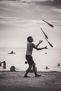 person juggling wooden sticks on beach shore thumbnail