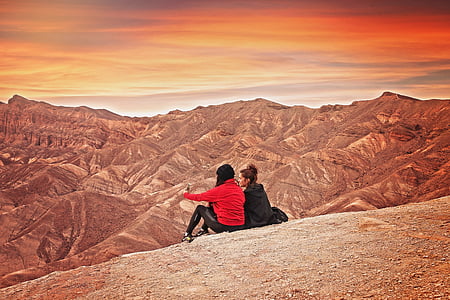 two women sitting on hill looking at hills thumbnail