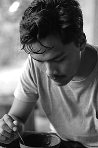 Gray Scale Photo of Man Holding Bowl and Spoon thumbnail