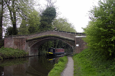 blue and red boat passing brown concrete bridge during daytime thumbnail