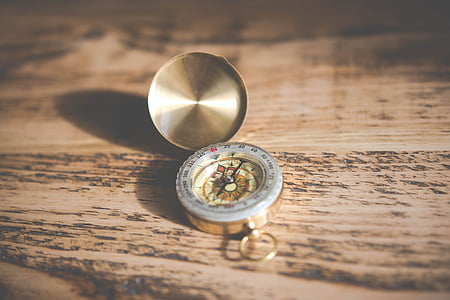 gold-colored compass on brown wooden surface thumbnail