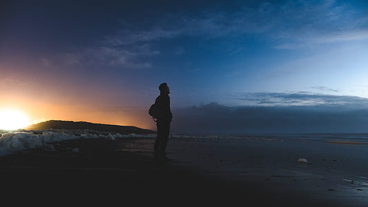 silhouette of man standing on shore thumbnail