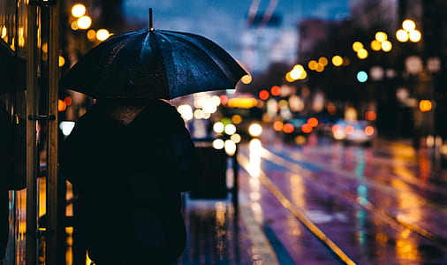 person holding black umbrella during night time thumbnail