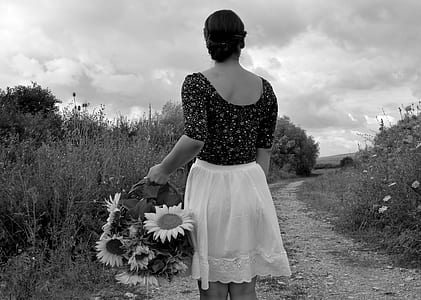 greyscale photography of woman holding basket with sunflower thumbnail