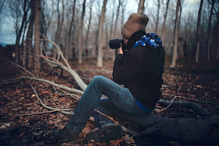 Man Wearing Black Jacket and Blue Jeans Sitting on Tree Branch thumbnail