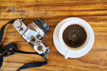 white ceramic teacup filled with coffee near gray DSLR camera thumbnail