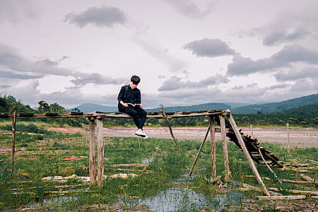 Man Sitting on Brown Wooden Bridge thumbnail