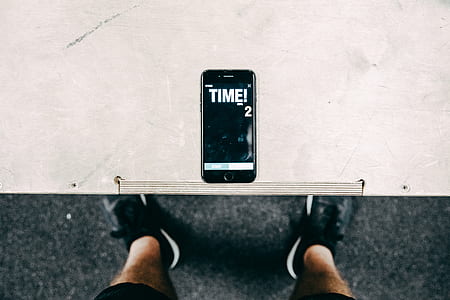 person standing beside table with iPhone displaying time 2 thumbnail
