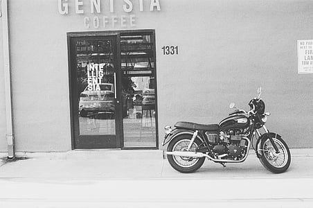 grayscale photo of motorcycle park outside coffee shop thumbnail