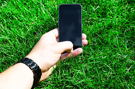 person holding black smartphone over green grass during daytime thumbnail