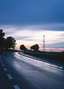 gray asphalt road in between green trees at daytime thumbnail