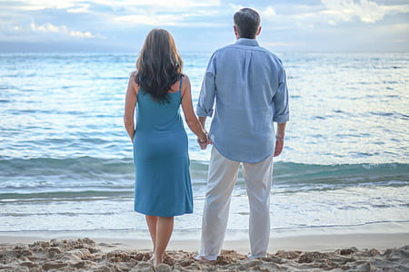 man and woman standing on shoreline while holding hands thumbnail