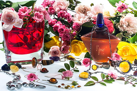 bottle near flowers and glass on white surface thumbnail