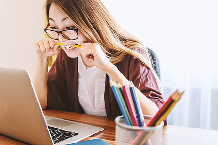 woman biting her pencil while facing computer thumbnail