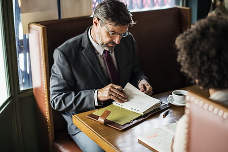 Man Sitting on Chair Writing Holding Notebook and Pen thumbnail
