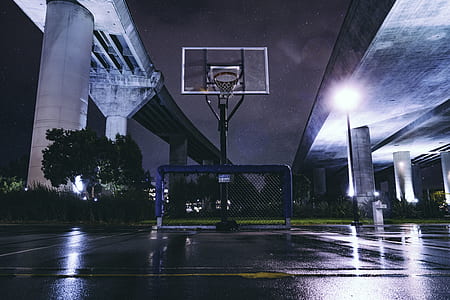 portable basketball hoop under bridge at nighttime photo thumbnail