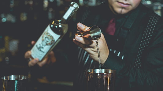 close-up photography of man wearing black suit holding bottle during daytime thumbnail