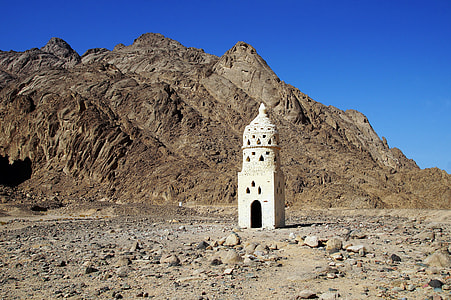 beige tower near brown mountain under blue sky thumbnail