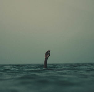 person raise hand in the middle of body of water thumbnail