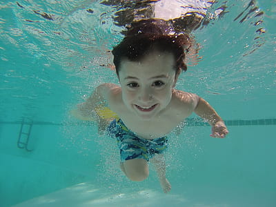 boy in blue shorts swimming on pool during daytime thumbnail