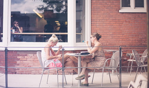 two women sitting on patio dining set beside brown concrete house thumbnail