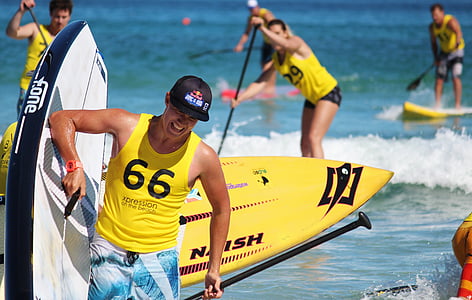 selective focus photography of woman carrying paddle board thumbnail